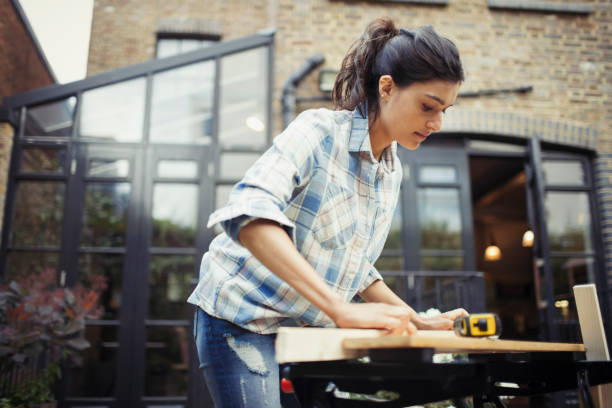 Jeune femme en train de bricoler dans son jardin pour installer un abri en bois